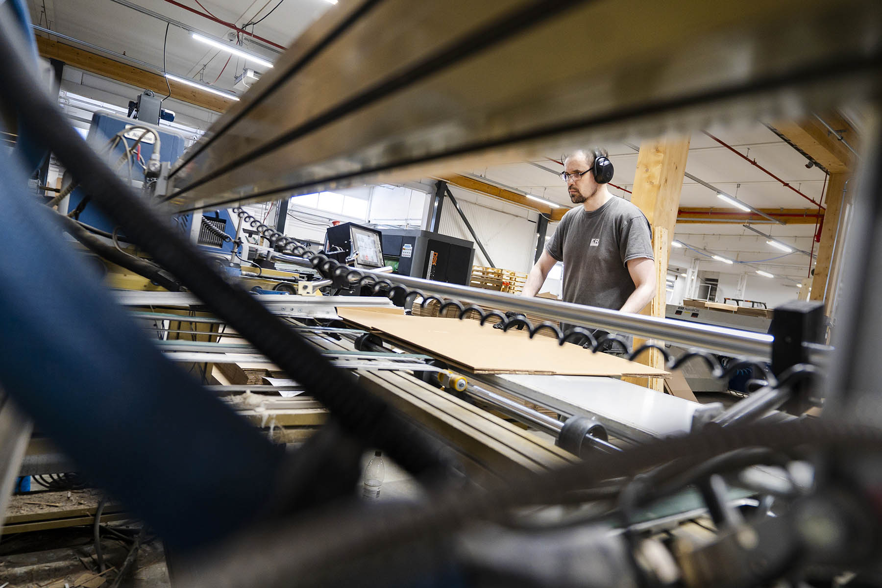 Tero Seppälä on taitellut aihion kaksin kerroin ja syöttää aihion liimakoneeseen, jossa kuuma liima kiinnittää telojen välissä puristuvat pinnat yhteen.
Mikko Toivio puhdistaa alipaineella ja liinalla mustesuuttimet, jotta painojälki pysyy toivotunlaisena.
Markus Miettinen havainnollistaa, kuinka aallotusta vastaan tehty nuuttaus taipuu pitkässä pakkauksessa toivotulla tavalla ja tekee tehtävänsä: suojaa tuotetta.
Petri Pääkkönen leikkurilla.