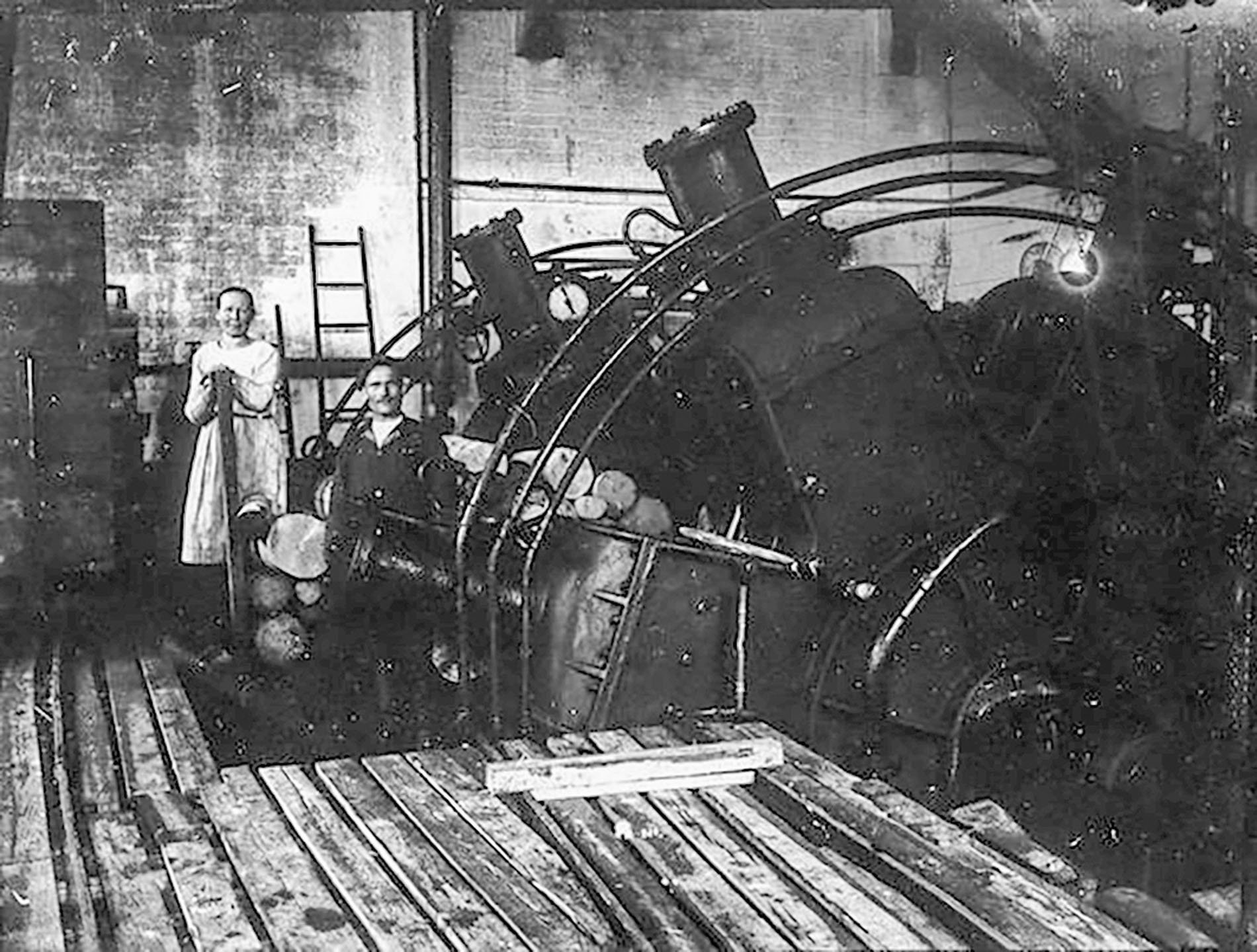 Voikkaan tehtaan puuhiomon vaaka-akselinen hiomakone ja kaksi työntekijää. Kuva otettu 1920-38.